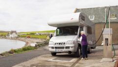 An overcab motorhome being filled up at a garage