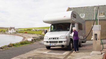 An overcab motorhome being filled up at a garage