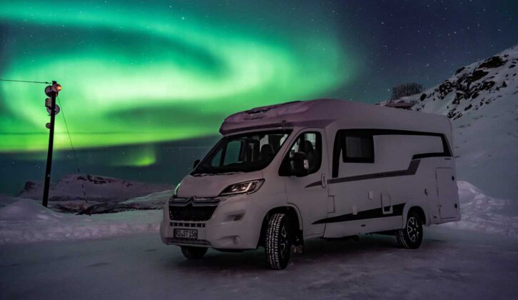 A motorhome with the Northern Lights in the background