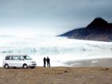 A couple standing by their campervan enjoying the view in Iceland