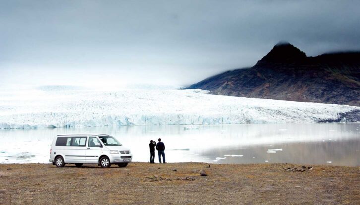 A couple standing by their campervan enjoying the view in Iceland