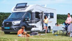 A publicity shot of a Voyager pitched up on grass while a family with a dog enjoy a picnic