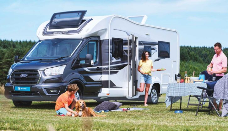 A publicity shot of a Voyager pitched up on grass while a family with a dog enjoy a picnic