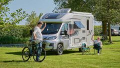 Peter with a bike waving to someone relaxing outside their motorhome