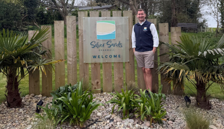 A man standing by the Silver Sands Holiday Park sign