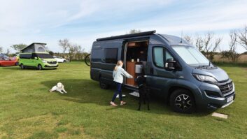 A dog in the shade of a pitched up campervan